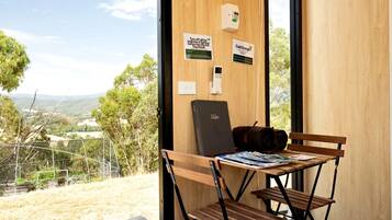 A room with a wooden desk, a laptop, and a bench. There are signs on the wall indicating temperature and energy-saving tips.