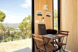Habitació amb escriptori de fusta, un ordinador portàtil i una banca. Hi ha indicadors murals que mostren la temperatura i consells per estalviar energia.