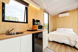 A compact room with a kitchenette, a bed, and a window with a view. - Elevated Tiny House with Valley and Vineyards Views in Victoria (Steels Creek)
