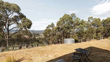 A fenced outdoor area with a metal bench and a wooden deck.