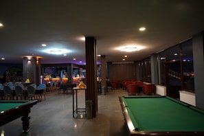 A billiards room with a pool table, chairs, and a bar area with a bartender. - Emin Kocak Kapadokya Termal Hotel (Ürgüp)