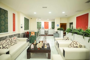 Un hall de hotel con mostrador de recepción, zona de estar y paneles decorativos en la pared.