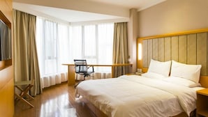 Quarto de hotel com uma cama grande, uma escrivaninha e uma cadeira.