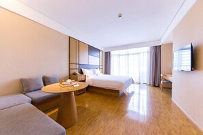 Une chambre d’hôtel avec un lit, un canapé, une petite table et un téléviseur.