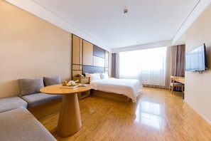 A modern hotel room with a bed, sofa, bedside table, and a TV. - JI Hotel Shanghai Hongqiao Transport Hub Jiuting (Shanghai)