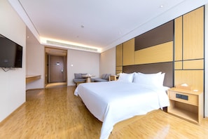 Ein modernes Hotelzimmer mit einem großen Bett, Nachttischen, einem Flachbildfernseher und einer Sitzecke mit Sofa und Tisch.