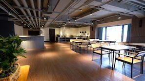 A spacious room with a long wooden table and chairs, a reception desk, and a kitchen area. - Chiilih Hotel- Su ao (Suao)