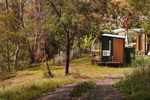 A secluded outdoor area with a small wooden structure, possibly a shed, and a grill on a raised platform.