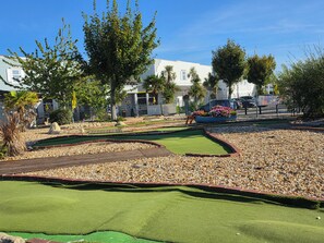 A miniature golf course with a putting green, sand traps, and a flower bed. - Lovely 3-Bedroom Caravan at Rockley Park.
Perfect for family stay. (Poole)