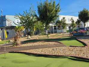 Ein Minigolfplatz mit Putting Green, Sandbunkern und einer Holzbrücke.