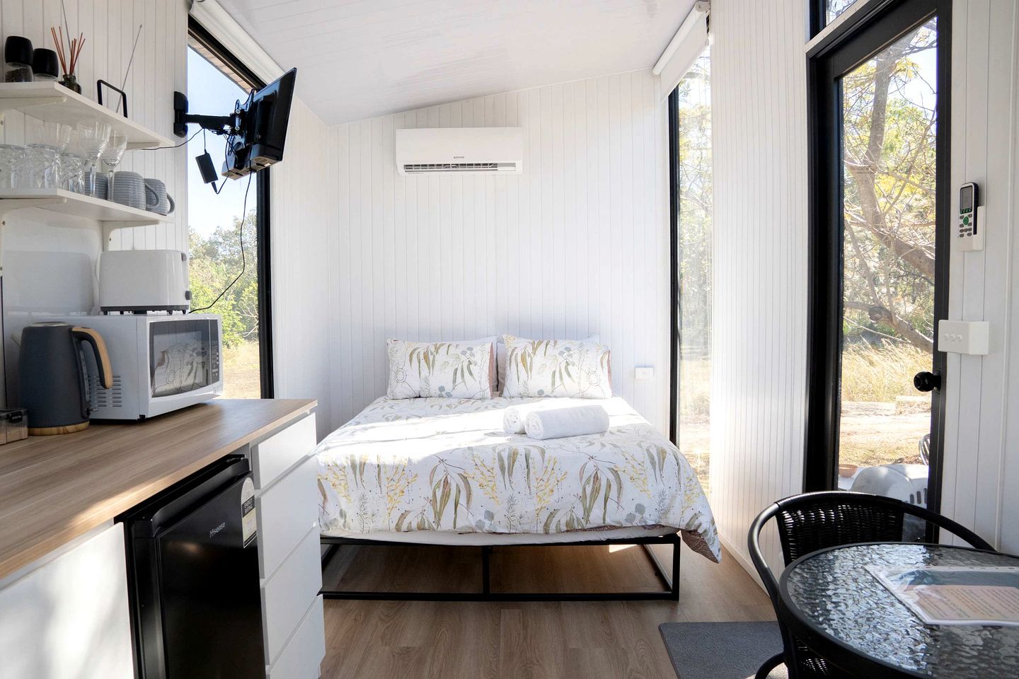 A compact room with a bed, a microwave, a kettle, and a small table.