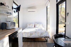 A compact room with a bed, a microwave, a kettle, and a small table.