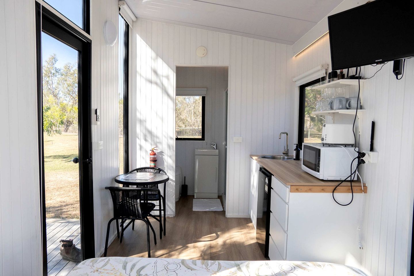 A compact kitchen with a microwave, sink, and a small dining area with chairs.