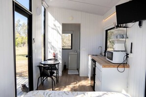 A compact kitchen with a microwave, sink, and a small dining area with chairs.
