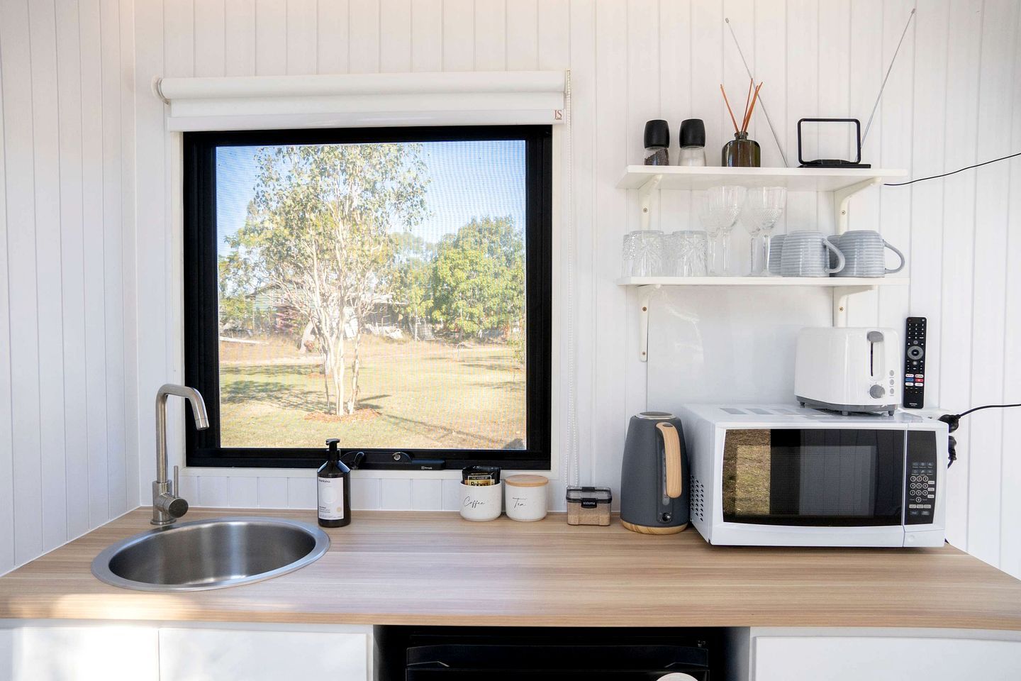 A kitchen with a large window, a sink, a microwave, and a toaster.
