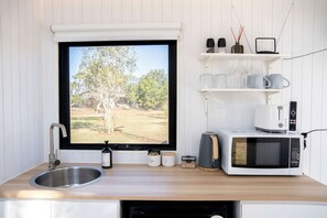 A kitchen with a large window, a sink, a microwave, and a toaster.