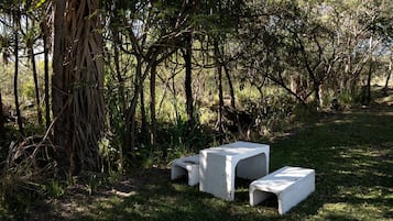 Two concrete benches in a natural setting with trees and grass.