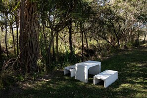Two concrete benches in a natural setting with trees and grass.
