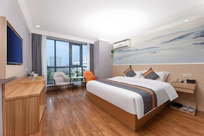 A hotel room with a large bed, a desk, a chair, and a window with a city view. - Greentree Alliance Huzhou Changxing Zhebei Business Square Hotel (Huzhou)
