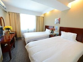 Una habitación de hotel con dos camas individuales, un escritorio con computadora, una silla y una ventana con cortinas.
