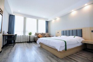 Una habitación de hotel moderna con una cama grande, un escritorio y una pequeña mesa.
