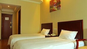 A hotel room with two single beds, a wooden headboard, a bedside table with a phone, and a painting on the wall. - Greentree Inn Xuancheng Langxi Guogou Plaza North Gate Express Hotel (Xuancheng)