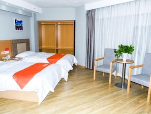 Ein Hotelzimmer mit zwei Betten, einem Schrank, einer Sitzecke mit Tisch und einer Zimmerpflanze.