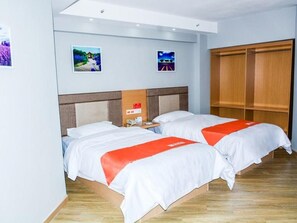 Ett hotellrum med två sängar, en garderob i trä och konst på väggen.