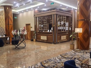 A lobby with a reception desk, a decorative wall, and a patterned carpet. - Anova Hotel (Riyadh)