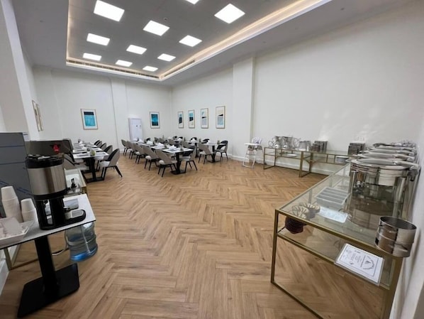 A conference room with tables, chairs, and a coffee station. - Anova Hotel (Riyadh)