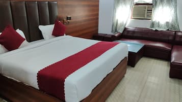 Habitación de hotel con cama, sofá, una mesita y una lámpara de pared.