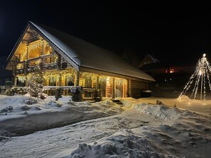 Eine Blockhütte mit schneebedecktem Dach und Außenbeleuchtung.