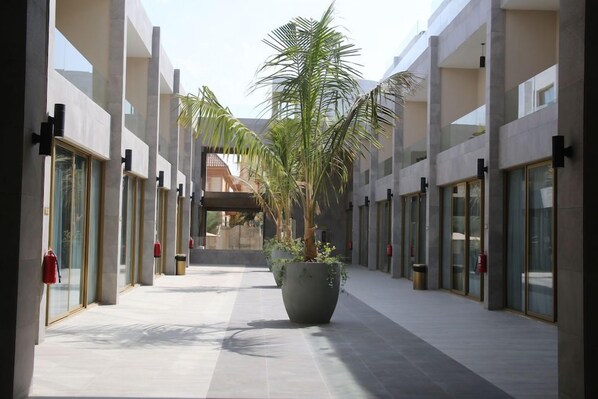 A corridor with a central planter, glass doors, and a clear sky. - Mirada Gold - Obhur (Jeddah)