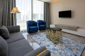 Una sala de estar moderna con un sofá, dos sillones, una mesa de centro y un televisor de pantalla plana montado en la pared.