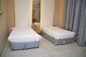A hotel room with two beds, a nightstand, and a mirror. - Mirada Gold - Obhur (Jeddah)