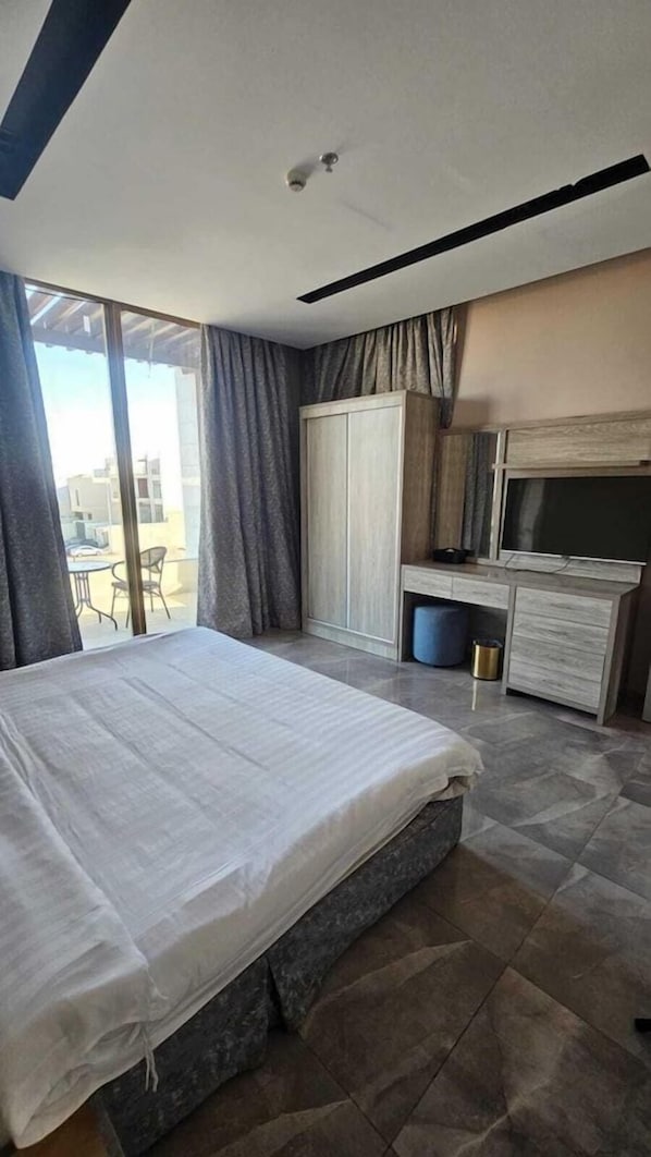 A hotel room with a bed, a TV, a wardrobe, and a view through the window.