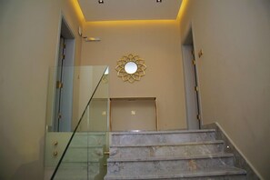 A staircase with a glass railing leading to a landing with a decorative wall piece. - Mirada Gold - Obhur (Jeddah)
