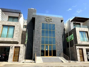 A modern building with a prominent entrance, large windows, and a flag.