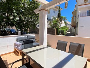 Eine Terrassengruppe im Freien mit Tisch und Sofa, umgeben von viel Grün und blauem Himmel.