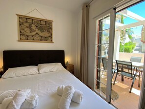Ein Hotelzimmer mit einem großen Bett, einem Wandbild einer Weltkarte, einem Balkon mit Tisch und Stühlen und Blick ins Freie.