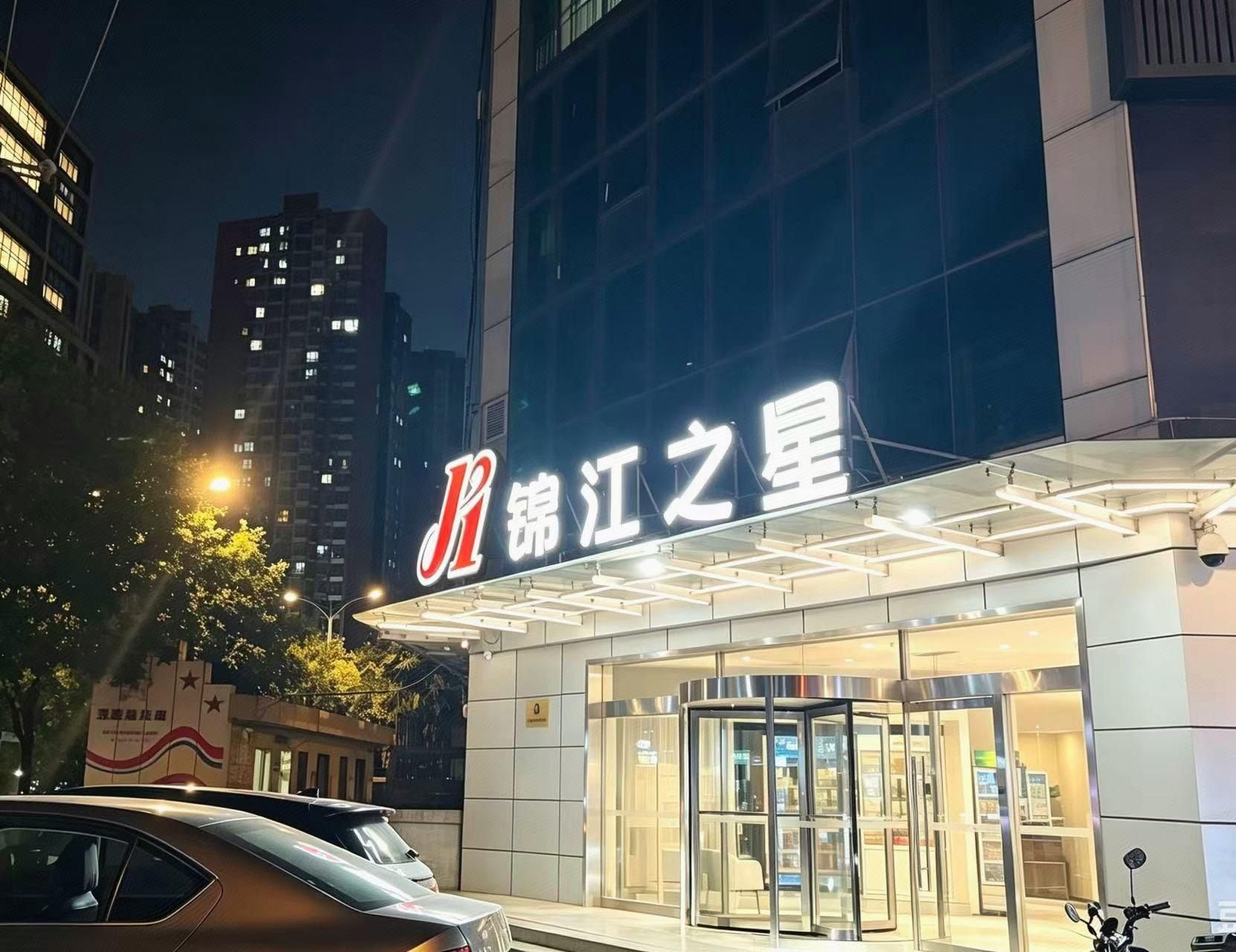 A hotel entrance with a revolving door and a sign with Chinese characters.