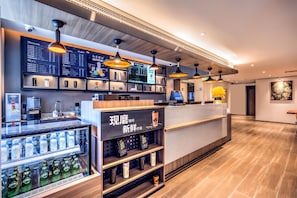A modern coffee shop interior with a digital menu board, beverage dispensers, and a seating area. - Vienna Hotel (Tianjin)