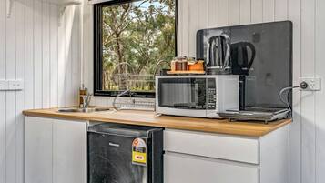Une petite cuisine équipée d’un four à micro-ondes, d’un grille-pain et d’un petit réfrigérateur.