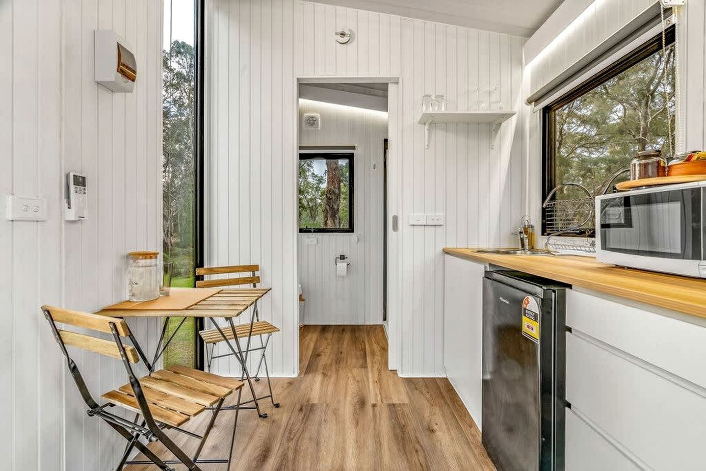 Une cuisine compacte avec une table et des chaises en bois, un four à micro-ondes et un lave-vaisselle.