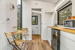 A compact kitchen with a wooden table and chairs, a microwave, and a dishwasher.