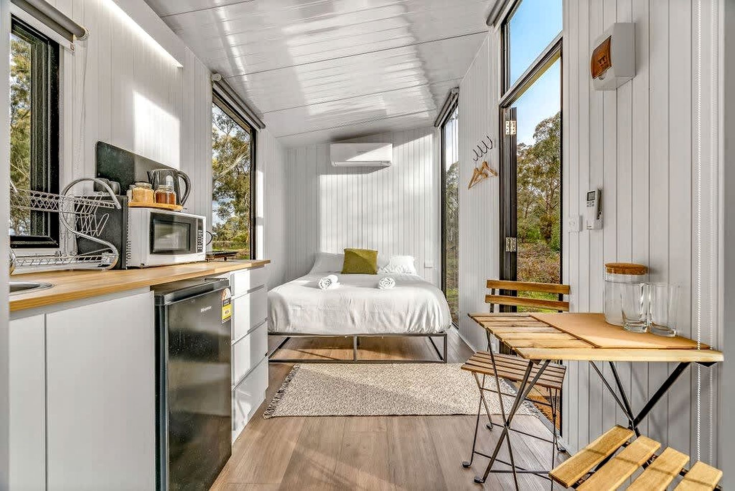 A compact bedroom with a bed, bedside table, and a view of the outdoors.