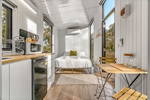 A compact bedroom with a bed, bedside table, and a view of the outdoors.