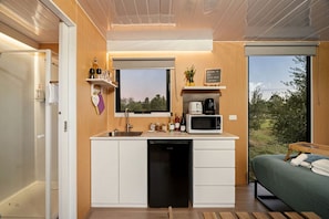 A compact kitchenette with a microwave, coffee maker, and sink. - Serene Tiny House with Amazing Countryside Landscapes in New South Wales (West Wyalong)