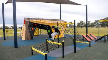 A playground with climbing structures, a net bridge, and a slide.