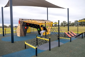A playground with climbing structures, a net bridge, and a slide. - Serene Tiny House with Amazing Countryside Landscapes in New South Wales (West Wyalong)